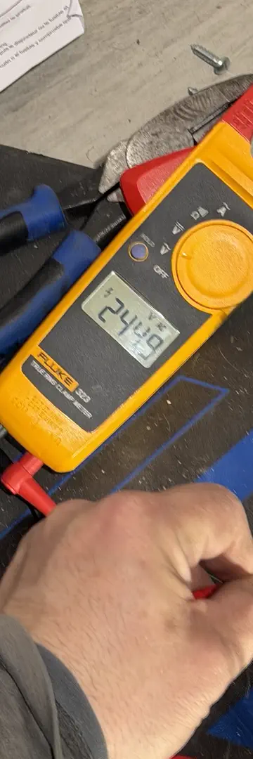 A clamp meter reading 244.9 volts, its leads on a newly wired receptacle